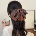 Eleganter Satin-Bogen-Haarclip mit Blumenmuster und Kristallanhängern auf Haar - Braun