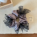 Détail d'un chouchou en satin mauve avec bordure en maille à pois noirs sur tissage - Violet