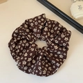 Dettaglio di un elastico marrone caffè con fiori bianchi su tavolo minimalista - Caffè Floreale