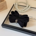 Close-up of elegant black knitted bow hair clip with sparkling rhinestone flower and plastic claw - Black