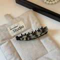 Détail d'une élégante pince banane en acétate avec motif marbré noir et blanc sur lin - Léopard Clair