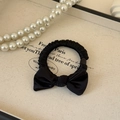 Detalle del coletero de satén negro con lazo elegante en bandeja de exhibición - Lazo del Pelo Negro