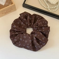 Dettaglio di un elastico per capelli in chiffon a fiori marroni su un vassoio vintage - caffè