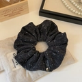 Detail van bloemenstof scrunchie met een gouden hart hanger en geweven merklabel - Zwart