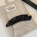 Dettaglio fermaglio per capelli in tessuto floreale con logo dorato su sacchetto - Bianco e Nero Picchiettato