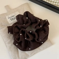 Dettaglio ravvicinato dell'elastico scrunchie marrone scuro con eleganti perle bianche applicate - Marrone