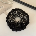 Detailed close-up of floral lace hair scrunchie with layered fabric and white flower pattern - Black