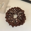 Close-up of coffee brown floral scrunchie with layered hollow lace and vintage pattern - Brown