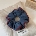 Detalle de coletero de punto azul oscuro con borde rojo sobre tela de lino elegante - Azul
