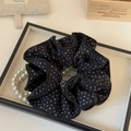 Macro detail of black floral scrunchie on white display tray with pearl necklace - Black