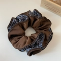 Dettaglio dello scrunchie marrone vintage con bordi pieghettati su sfondo bianco - Caffè
