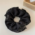 Dettaglio ravvicinato di un elastico in seta nera con delicati motivi floreali bianchi - Nero a Quattro Strati