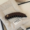 Detailaufnahme einer Vintage Bananen-Haarklammer mit Leopardenmuster und goldenem Logo - Braun