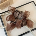 Dettaglio dell'elastico per capelli in velluto marrone con strass e fiocco in organza - caffè