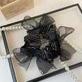 Dettaglio dell'elastico scrunchie in raso nero e organza con paillettes e fiocco - Nero