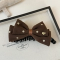 Detail of coffee brown polka dot bow hair clip with a gold handmade heart charm - Brown