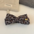 Detalle de pinza para pelo con lazo de leopardo gris y placa dorada en fondo blanco - Estampado de Leopardo Gris