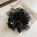 Detalle de un elegante coletero negro con capas de organza y patrón de lunares blancos - Negro
