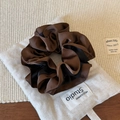Détail d'un chouchou en satin bicolore avec bords à volants sur fond de lin rustique - Patchwork Café et Noir