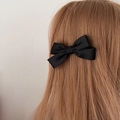 Elegant black satin bow hair clip for women styled on long brown hair in a side view - Black Satin Ribbon Bow