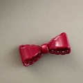 Close-up of a glossy red bow hair clip with decorative hollowed-out scalloped edges - Red