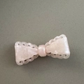 Detail of pink resin bow hair clip featuring intricate hollowed-out lace edges - Pink
