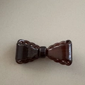 Detail of dark brown bow hair clip featuring an openwork lace edge and a glossy finish - Brown