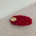 Nahaufnahme einer Haarspange aus rotem Tweed mit ovalem goldenem POKO FOSCA Metalllogo - Ovales Etikett