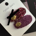 Dettaglio di fermagli per capelli in tweed e pile con etichette dorate su carta - Viola