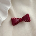 Gros plan d'un nœud à cheveux rouge bordeaux avec bords ondulés sur tissu de soie - Rouge Nouvel An - Nœud Bord Ajouré