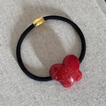 Dettaglio di elastico per capelli nero con cilindro in metallo dorato e farfalla glitterata rossa - Farfalla Piccola