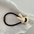 Detalle de un lindo dije de conejo crema en una goma de pelo elástica negra - Amarillo Crema