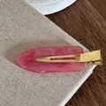 Vue macro détaillée d'une pince à cheveux en résine marbrée rose avec base en métal doré - rose vif