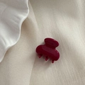 Gros plan détaillé d'une mini pince à cheveux rouge baie brillante sur un fond en tissu épuré - Rouge Nouvel An - Mini Pince Cintre