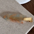 Detail of cellulose acetate hair clip with orange and gold marble pattern on linen - Orange Green