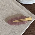 Gros plan d'une barrette à paillettes roses avec base en métal doré sur tissu rustique - Rose Pailleté