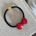 Dettaglio dell'elastico per capelli con fiocco rosso glitter e fibbia in metallo oro - Fiocco