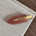 Détail d'une barrette en résine marron rouge avec paillettes fines et base dorée - Orange Pailleté