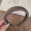 Nahaufnahme eines kaffeebraunen Schwamm-Haarreif mit Hand-Made-Label und weichem Stoff - Braun