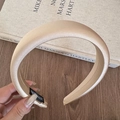 Close-up of champagne gold satin padded headband with handmade label on vintage book - Apricot