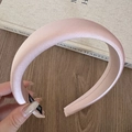 Close-up of pink satin padded headband with detailed texture and brand woven label - Light Pink