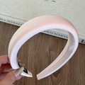 Detail of light pink padded headband with satin texture on a wooden table setup - Nude Pink