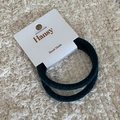 Close-up of two dark velvet elastic hair ties on a minimalist white handmade brand card - Green