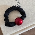 Dettaglio di un elastico per capelli nero con una grande perla decorativa rossa lucida - Scrunchie Palla Rossa - Grande