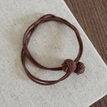 Dettaglio dell'elastico per capelli intrecciato marrone scuro con nodi sferici eleganti - Caffè Chiaro