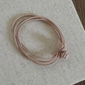 Detailed macro view of four-strand elastic hair tie with soft pink woven bead knots - Apricot