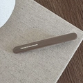Detailaufnahme einer braunen handgefertigten Haarspange mit silbernem France-Schriftzug - Khaki