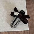 Detail einer braunen Samtschleife-Haarklammer mit Strass und Logo-Metallplakette - Kaffeebraun