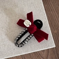 Detailed shot of a red velvet bow hair clip with sparkling rhinestones and metal label - Red