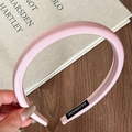 Detailed view of pink satin padded headband with black handmade label on vintage book - Light Pink